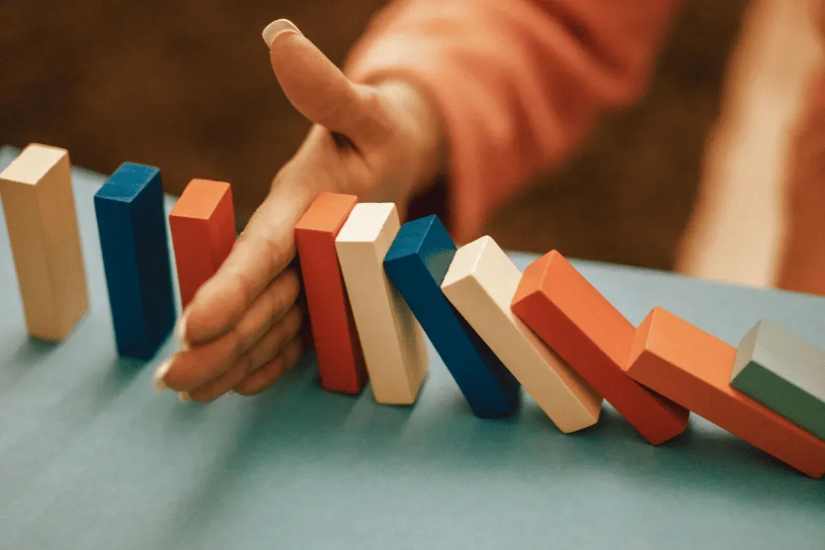 Main arrêtant une chute de dominos, image du budget publicitaire gardé sous contrôle